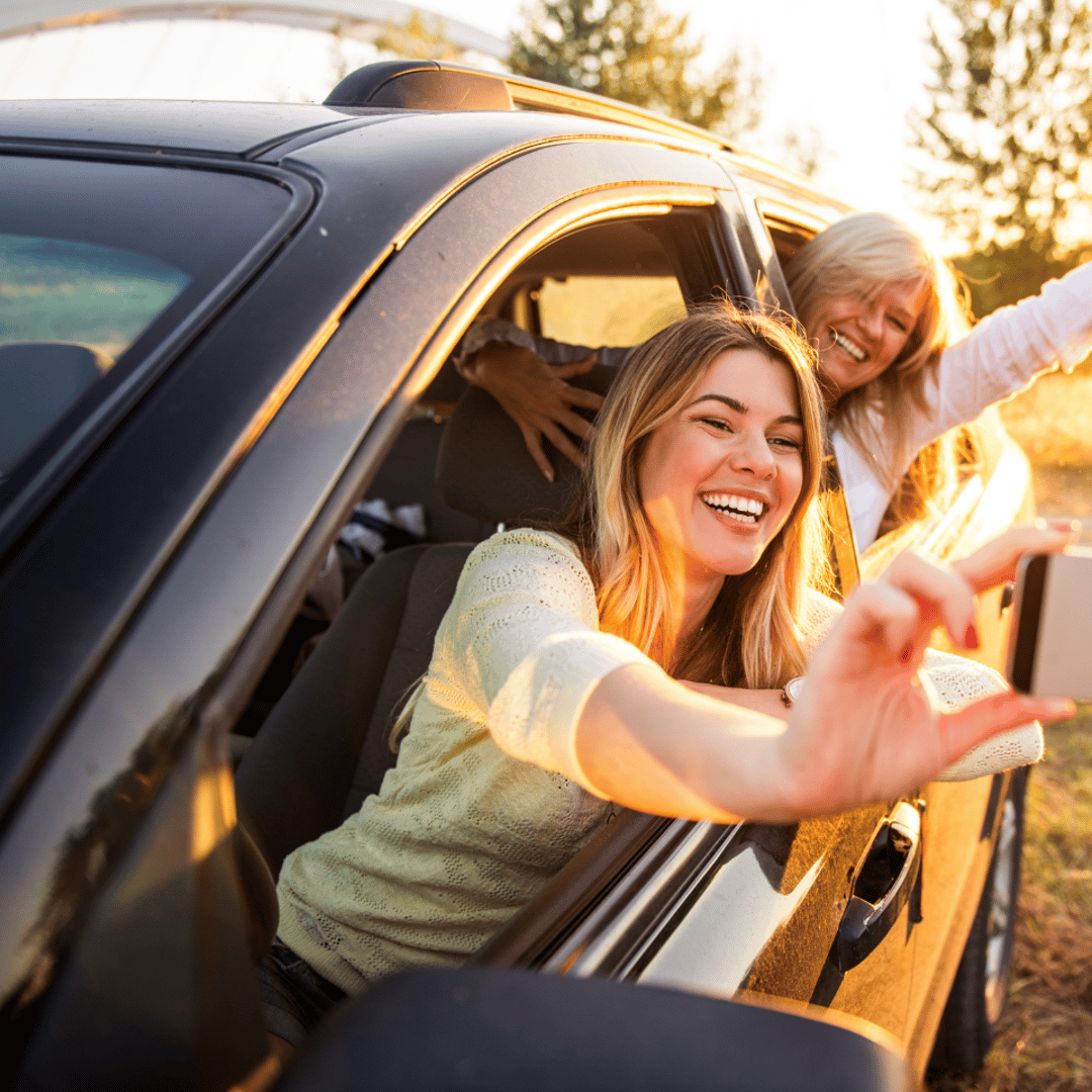 Eine Familie sitzt im Auto. Die Mutter schaut zu den Kindern. Sie hält eine Karte in der Hand.